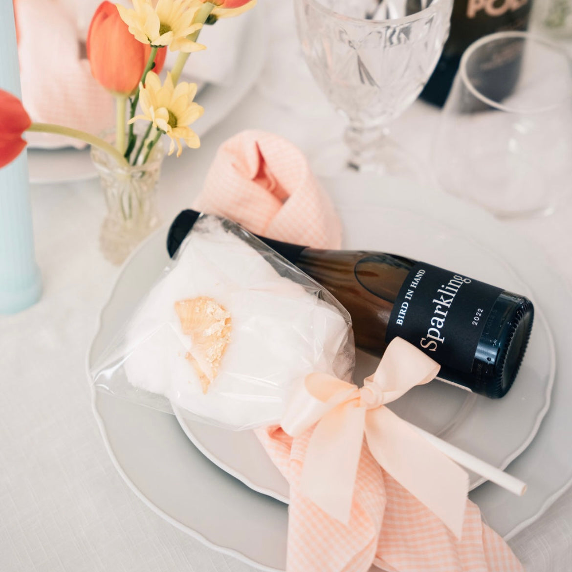 A fairy floss stick presented on a plate with a glass of sparkling wine, suitable for an event.